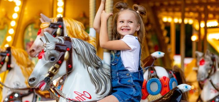a child smiles while riding a horse on a carousel